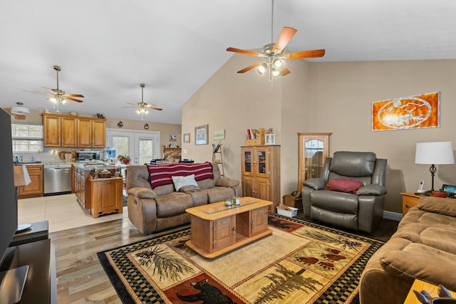 living room with sink, light hardwood / wood-style flooring, french doors, and high vaulted ceiling