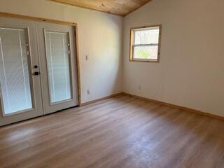 spare room featuring french doors, baseboards, vaulted ceiling, and wood finished floors