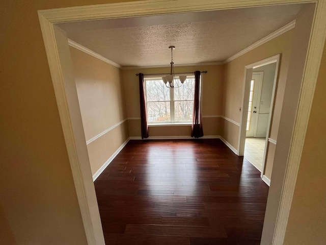 unfurnished dining area with dark wood-type flooring, ornamental molding, and a textured ceiling