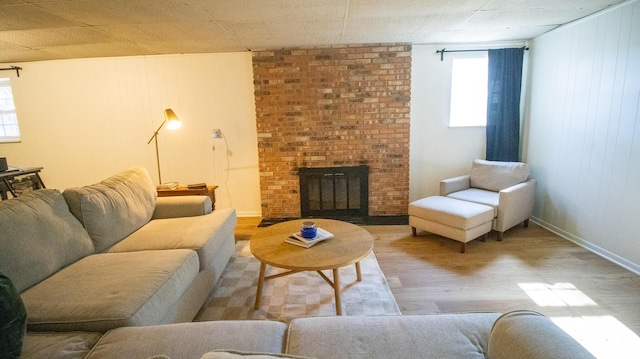 living room with a wealth of natural light, a brick fireplace, baseboards, and wood finished floors