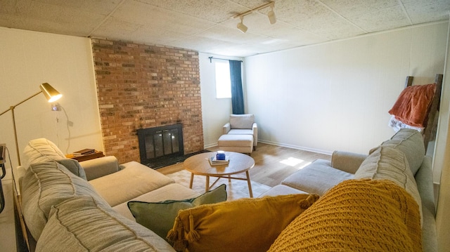 living area featuring a brick fireplace, baseboards, and wood finished floors