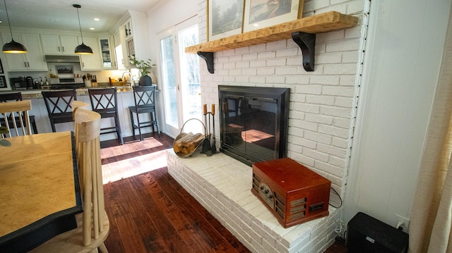 living room featuring recessed lighting, a healthy amount of sunlight, a brick fireplace, and dark wood-type flooring