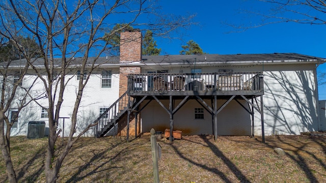 back of property with a wooden deck, stairway, brick siding, and a chimney