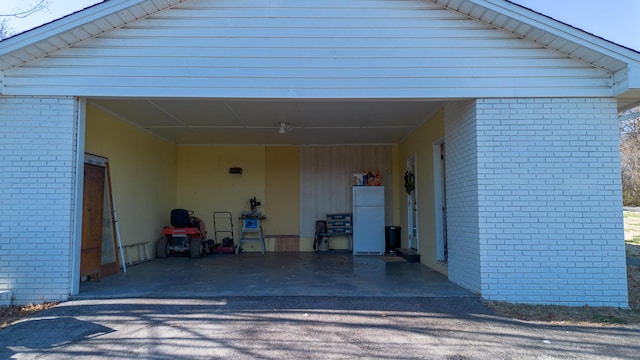 garage featuring driveway and freestanding refrigerator