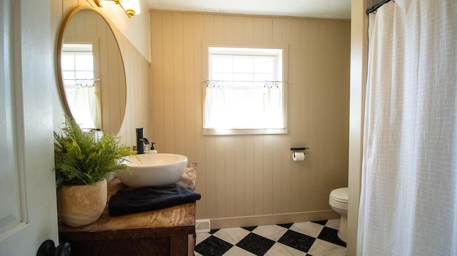 full bath featuring tile patterned floors, toilet, a healthy amount of sunlight, and baseboards