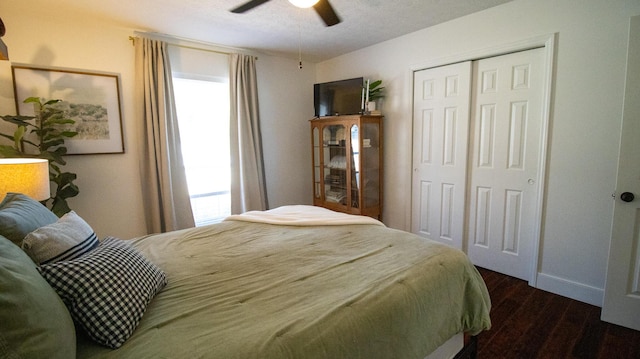 bedroom featuring multiple windows, a ceiling fan, dark wood-style flooring, and a closet