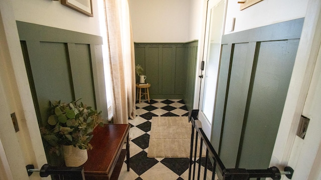 hallway featuring tile patterned floors, wainscoting, and a decorative wall