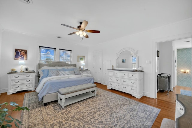 bedroom with ceiling fan, ornamental molding, and wood finished floors
