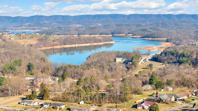 aerial view featuring a water and mountain view and a wooded view