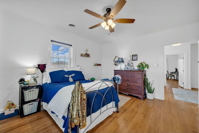 bedroom featuring baseboards, a ceiling fan, visible vents, and light wood-style floors