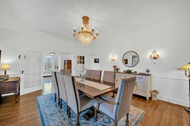 dining area with an inviting chandelier, ornamental molding, french doors, and wood finished floors