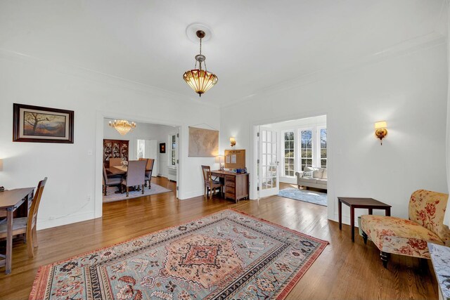 interior space with a chandelier, wood finished floors, crown molding, and french doors