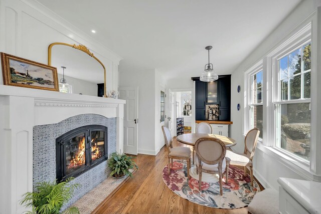 dining area with a glass covered fireplace, baseboards, and wood finished floors