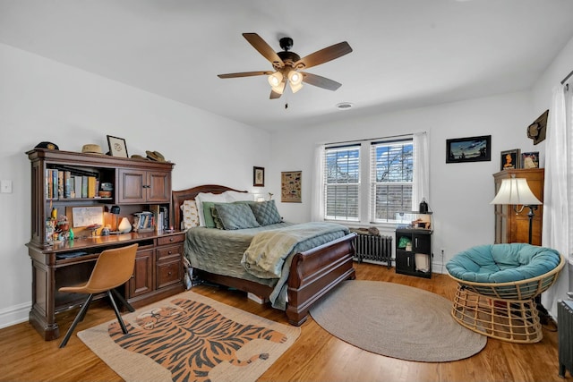 bedroom featuring light wood-style flooring, visible vents, a ceiling fan, and radiator