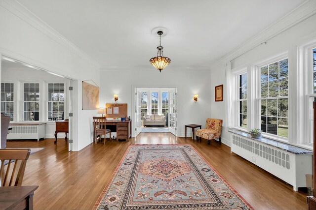 foyer with radiator heating unit, crown molding, baseboards, and wood finished floors