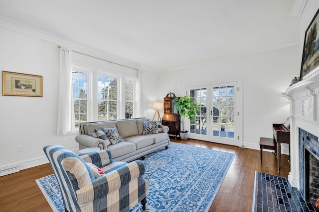living area featuring a fireplace with flush hearth, wood finished floors, baseboards, and ornamental molding