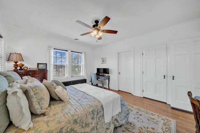 bedroom with a ceiling fan, wood finished floors, and radiator