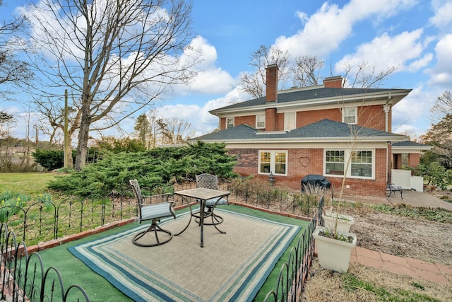 back of house featuring a chimney, brick siding, and a patio