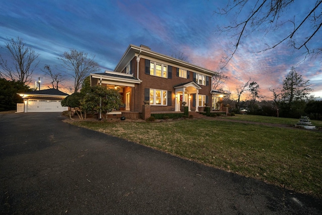 colonial home with an outbuilding, brick siding, a front yard, and a garage