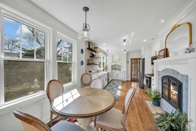 dining area with a fireplace with flush hearth, recessed lighting, and light wood-type flooring