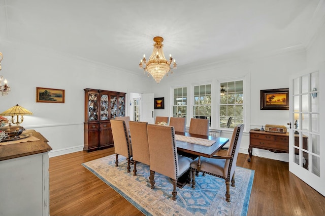 dining room featuring wood finished floors, ornamental molding, and a notable chandelier