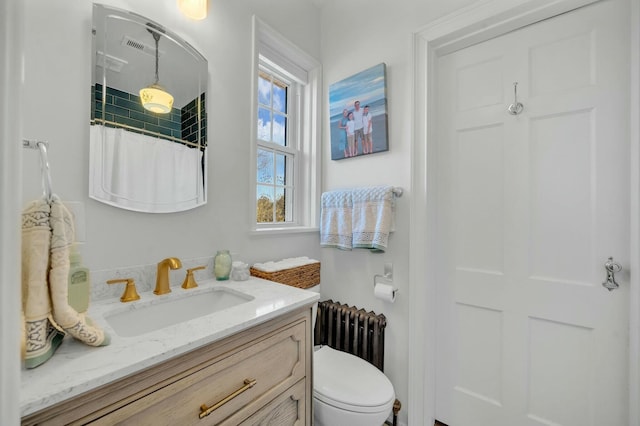 bathroom with radiator, toilet, visible vents, a shower with shower curtain, and vanity