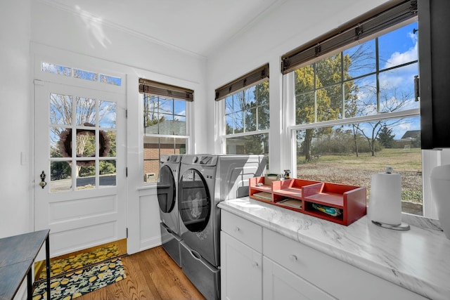 clothes washing area featuring light wood-type flooring, washer and clothes dryer, laundry area, and ornamental molding