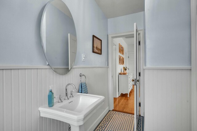 bathroom with wooden walls, tile patterned floors, a sink, and wainscoting
