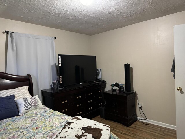 bedroom with a textured ceiling and dark wood-type flooring