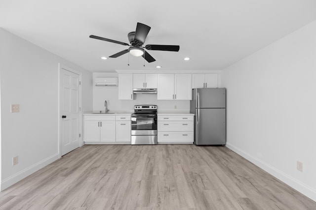 kitchen with sink, stainless steel appliances, a wall mounted air conditioner, light hardwood / wood-style flooring, and white cabinets