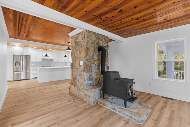 living room featuring beamed ceiling, wooden ceiling, a wood stove, and light hardwood / wood-style flooring