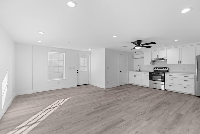 kitchen with sink, white cabinets, light wood-type flooring, and appliances with stainless steel finishes