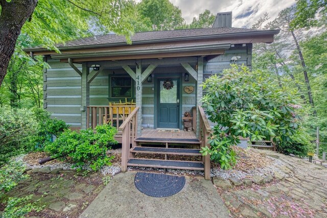entrance to property featuring a chimney and a shingled roof