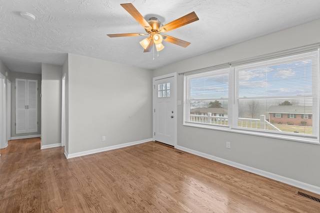 interior space featuring ceiling fan, wood-type flooring, and a textured ceiling