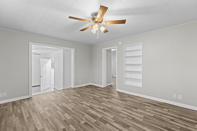 unfurnished room featuring ceiling fan, hardwood / wood-style floors, and built in features