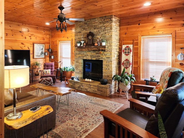 living room featuring a stone fireplace, wood-type flooring, wooden ceiling, and wooden walls