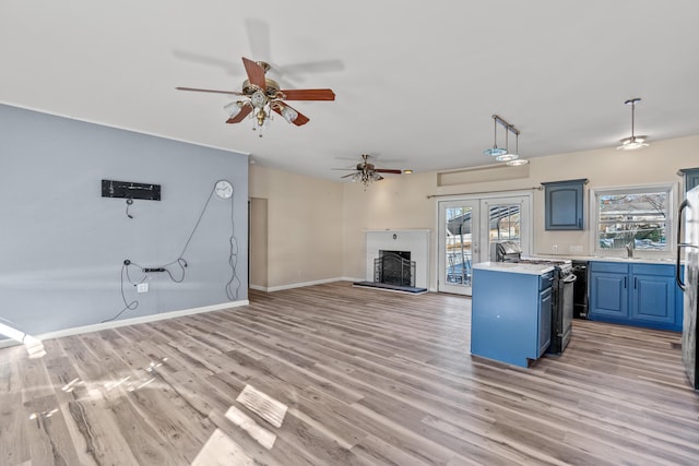 kitchen featuring stainless steel gas range, light hardwood / wood-style flooring, a center island, hanging light fixtures, and blue cabinets