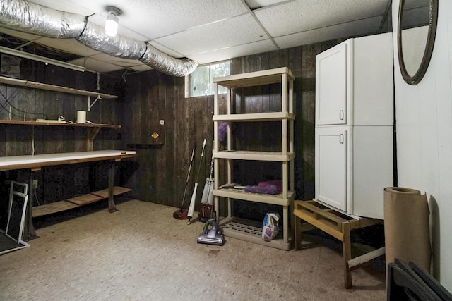 basement featuring wood walls and a drop ceiling