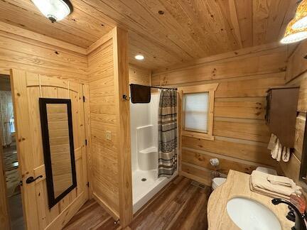 bathroom featuring hardwood / wood-style floors, wood walls, a shower with curtain, sink, and wood ceiling