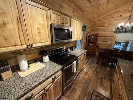 kitchen with wood walls, wooden ceiling, lofted ceiling, dark stone counters, and black electric range