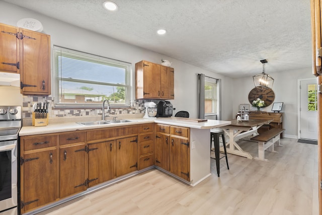 2121 Fir St, Morristown, TN 37813 - kitchen with a sink, light wood-type flooring, stainless steel electric range oven, a peninsula, and a textured ceiling