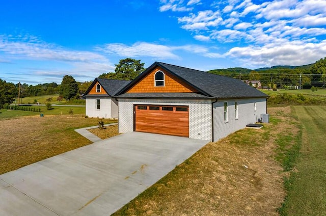 view of front of house featuring a mountain view, central air condition unit, and a front yard