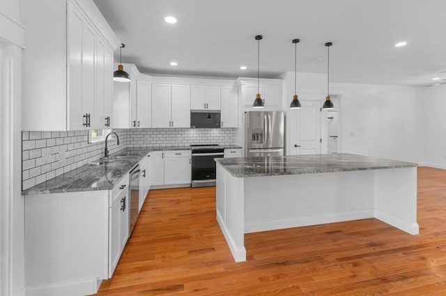 kitchen featuring white cabinets, a kitchen island, hanging light fixtures, and appliances with stainless steel finishes