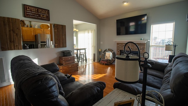 living room featuring a fireplace, light hardwood / wood-style floors, and lofted ceiling