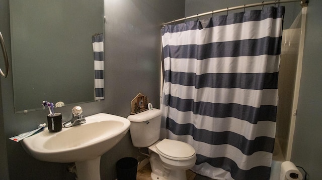 bathroom with curtained shower, toilet, and sink