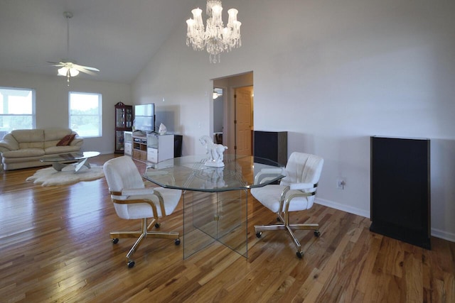 dining room with hardwood / wood-style flooring, ceiling fan with notable chandelier, and lofted ceiling