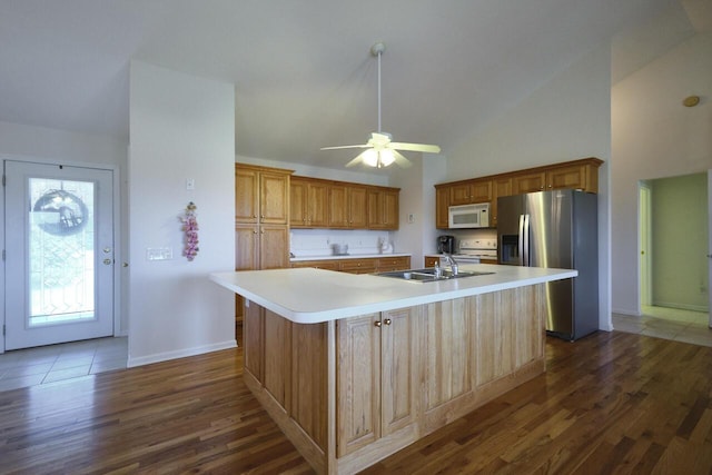 kitchen featuring vaulted ceiling, sink, an island with sink, and white appliances