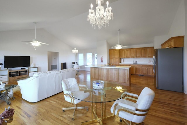 dining space featuring ceiling fan with notable chandelier, light wood-type flooring, and vaulted ceiling