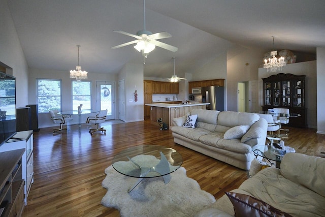 living room with ceiling fan with notable chandelier, dark hardwood / wood-style floors, and high vaulted ceiling