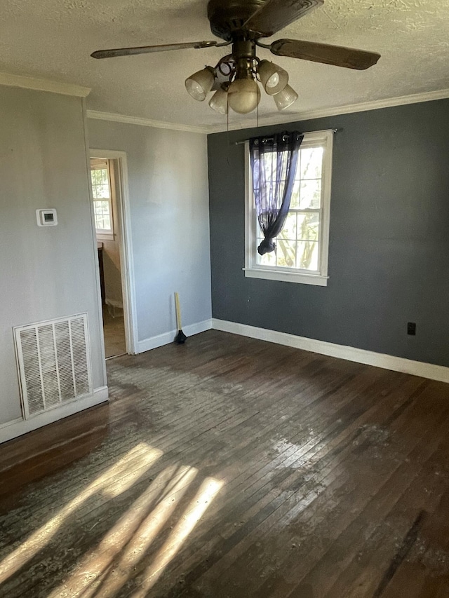 spare room with a textured ceiling, dark hardwood / wood-style flooring, and crown molding